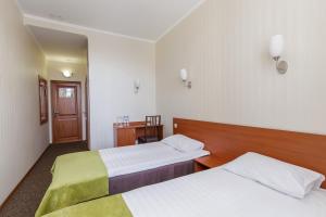 a hotel room with two beds and a desk at Hotel Avrora in Omsk