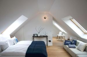 a white bedroom with a bed and a couch at Lieblingsplatz Strandhotel in Sankt Peter-Ording