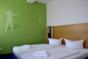 een groene kamer met 2 bedden en handdoeken erop bij Outdoor Inn Sporthotel Steinach in Steinach