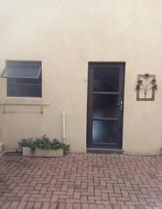a door to a building with a window and a potted plant at Woodpecker Guesthouse Middelburg Mpumalanga in Middelburg