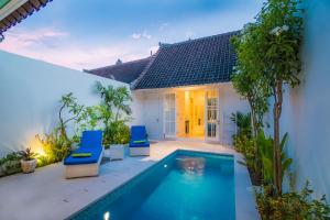スミニャックにあるVilla Ley Double Six by Best Deals Asia Hospitalityのスイミングプール、青い椅子2脚が備わるヴィラです。