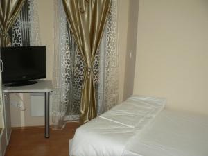 a bedroom with a bed and a tv and a curtain at Hotel Leder in Kočani