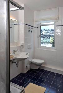 łazienka z umywalką, toaletą i oknem w obiekcie Outdoor Inn Sporthotel Steinach w mieście Steinach
