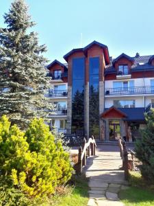 a large building with a tree in front of it at Hotel Skalny Spa Bieszczady in Polańczyk