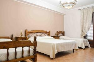 Hotel Castello di Giuliano في Montelepre: غرفة نوم بثلاث اسرة وثريا
