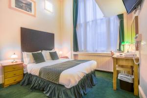 a bedroom with a bed and a desk and a window at London Town Hotel in London