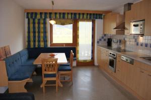 eine Küche mit einem blauen Sofa und einem Tisch mit Stühlen in der Unterkunft Appartements Schwoagerhof in Fügen