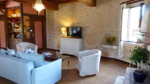 sala de estar con sillas blancas y TV en Hameau de Montcabirol en Mirepoix