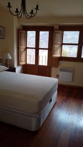 um quarto com uma grande cama branca num quarto com janelas em La Forna del Coto em Coto de Buenamadre