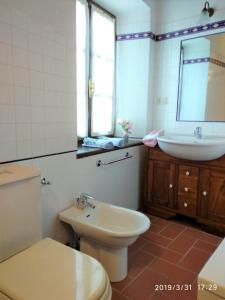 bagno con servizi igienici, lavandino e specchio di Casa Vittoria a Verni