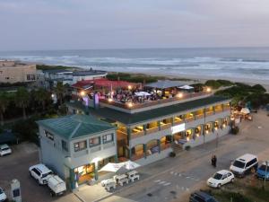 a building with a bar on top of it next to the ocean at Pili Pili Beach Cabanas in Sedgefield