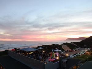 a group of people standing on top of a building at sunset at Pili Pili Beach Cabanas in Sedgefield