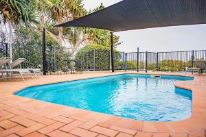 una piscina con sombrilla y algunas sillas en The Observatory Self Contained Apartments, en Coffs Harbour