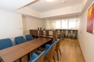 uma sala de conferências com uma longa mesa de madeira e cadeiras azuis em Homy Residence em Hong Kong