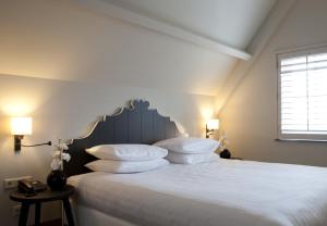 1 dormitorio con 1 cama con sábanas y almohadas blancas en Fletcher Hotel - Restaurant Nautisch Kwartier en Huizen
