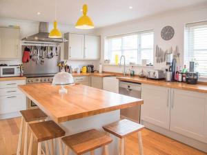 a kitchen with white cabinets and a wooden counter top at Honeybee Cottage in Orford