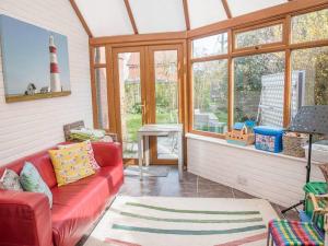 a living room with a red couch in front of a lighthouse at Honeybee Cottage, Orford in Orford