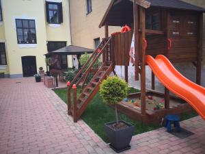 einen Spielplatz mit einer roten Rutsche und einer Spielstruktur in der Unterkunft Korzó Apartman in Kőszeg