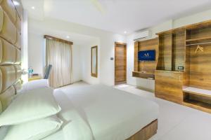 a bedroom with a large white bed and a tv at Aura One Hotel in Cochin