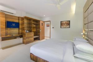 um quarto com uma cama branca e uma parede de madeira em Aura One Hotel em Cochin