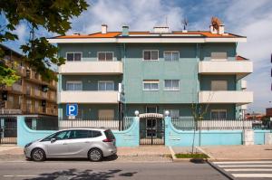 a car parked in front of a blue building at Apartamentos Turisticos Ceu Azul in Arcozelo