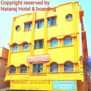 un edificio giallo con un cartello davanti di Nataraj Hotel and Boarding a Barddhamān