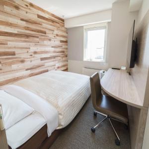 a bedroom with a wooden accent wall and a desk at Super Hotel Kushiro Natural Hot Spring in Kushiro