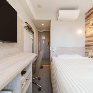 a room with two beds and a desk with a tv at Super Hotel Kushiro Natural Hot Spring in Kushiro