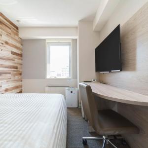 a bedroom with a desk and a tv on the wall at Super Hotel Kushiro Natural Hot Spring in Kushiro