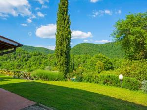 un jardín con un gran árbol y montañas en el fondo en Holiday Home I Lecci by Interhome, en Lucolena in Chianti