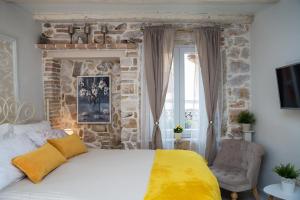 een slaapkamer met een bed en een stenen muur bij Studio Yellow Flower in Rovinj