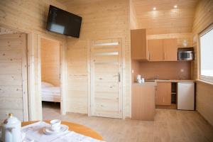 a kitchen with wooden walls and a room with a table at Domki Letniskowe Biała Perła in Jezierzany