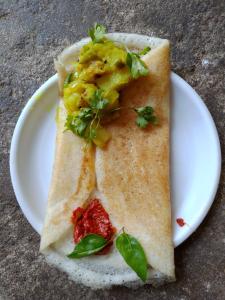 Un plato blanco con un trozo de comida. en Lakshmi Heritage Tourist Home, en Hampi