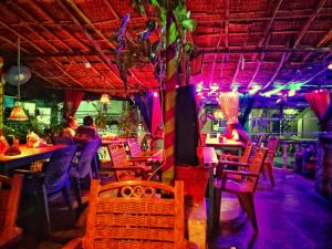 un restaurante con mesas, sillas y luces púrpuras en Lakshmi Heritage Tourist Home, en Hampi