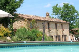 a stone house with a swimming pool in front of it at Il Nascondiglio - The Hideaway in Amandola