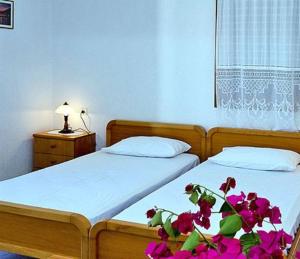 ein Schlafzimmer mit 2 Betten und eine Pflanze mit lila Blumen in der Unterkunft Marigoula Village in Skopelos