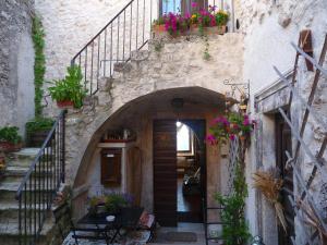 an entrance to a stone building with a staircase with flowers at La Bifora e Le Lune Vico sotto gli archi 5 in Santo Stefano di Sessanio
