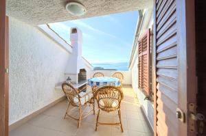 a balcony with a table and chairs and a view of the ocean at Apartment Galerija by El-Pi Tours in Njivice
