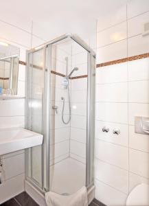 una doccia con porta in vetro in bagno di Hotel Lindenhof a Rödermark