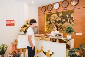 a man and a woman standing at a cash register at Hotel Royal in Vân Lũng