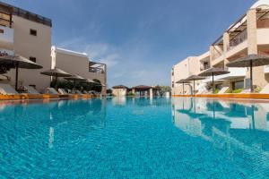 a large swimming pool with blue water in front of buildings at Olympion Sunset Halkidiki in Fourka