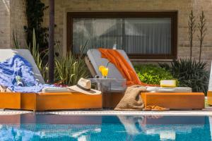 a pool with two chaise lounges next to a swimming pool at Olympion Sunset Halkidiki in Fourka