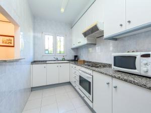 a kitchen with white cabinets and a microwave at Holiday Home Carlos by Interhome in Cambrils +13 photos