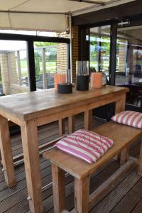 una mesa de madera y un banco en una habitación con ventanas en Fletcher Hotel - Restaurant Heiloo en Heiloo