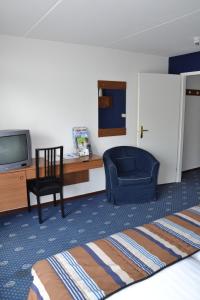 a hotel room with a bed and a tv and a chair at Fletcher Hotel - Restaurant Heiloo in Heiloo