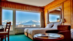 um quarto de hotel com uma cama, uma mesa e uma janela em Hotel-Restaurant Le Mont Paisible, Crans-Montana em Crans-Montana