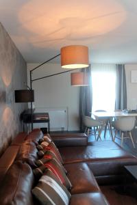 a living room with a leather couch and a table at Parkhotel Heidehof Long Stay in Ingolstadt