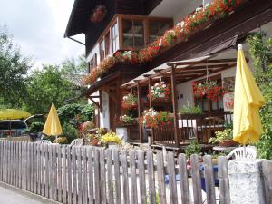 ein Gebäude mit einem Zaun, Stühlen und Sonnenschirmen in der Unterkunft Gaestehaus Richter in Oberammergau
