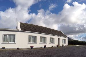 a white house with a black roof at Cosy Keel Cottage in Keel
