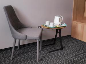 a table with a chair and a table with cups on it at Hotel Duet in Człuchów